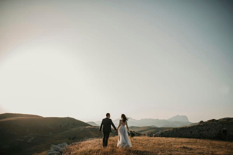 A couple holding hands while walking through the countryside