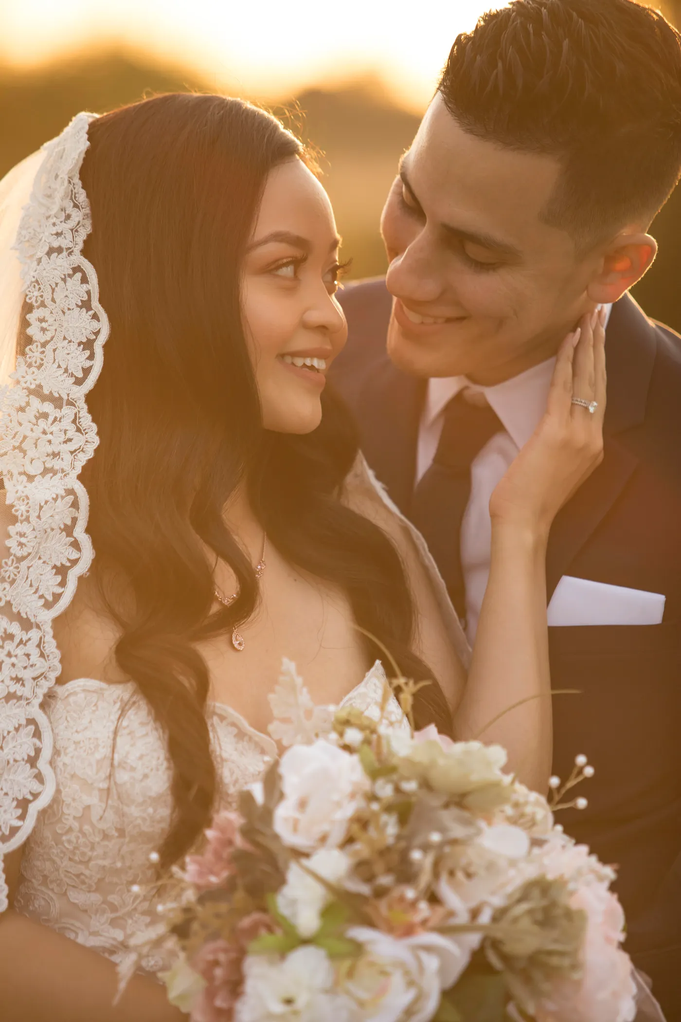 A bride and groom smiling at each other in warm sunset light